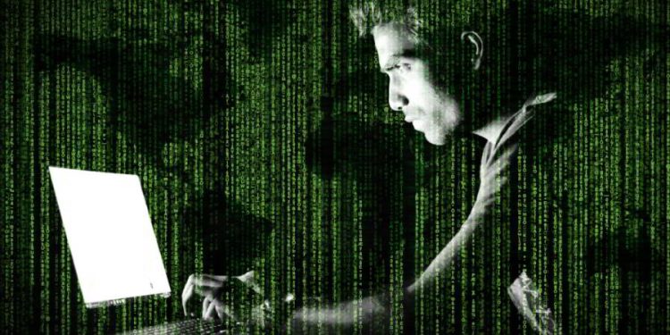 Hacker frente a computador, con código y mapa mundial. Imagen por Jack Moreh / stockvault.net