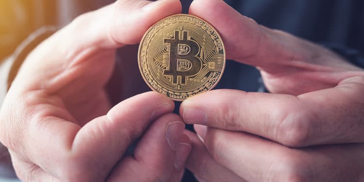 Hombre sosteniendo con ambas manos moneda de bitcoin. Fuente: stevanovicigor / elements.envato.com